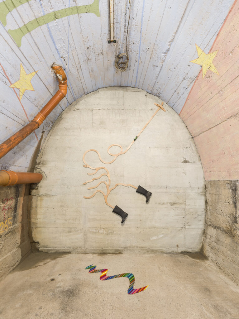 Installation view of different art works in an abbandoned tunnel with a painted ceiling.